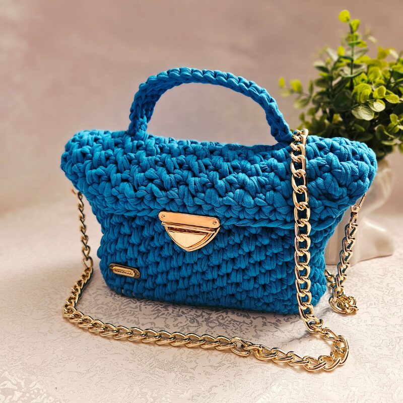 Türkiissinine heegeldatud käekott taaskasutatud trikotaažpaelast käepideme ja must-kuldse ketiga